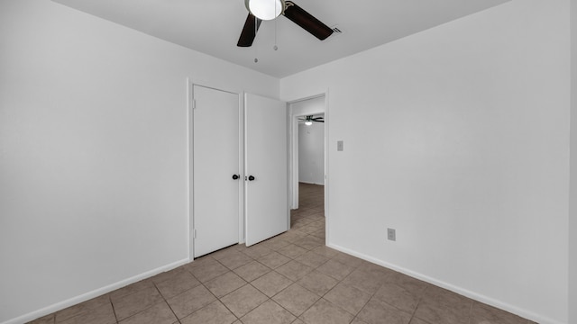 unfurnished bedroom featuring ceiling fan, a closet, and light tile patterned floors