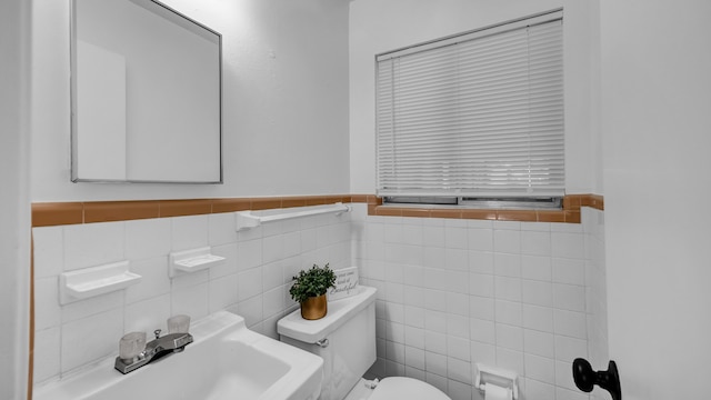 bathroom featuring sink, tile walls, and toilet