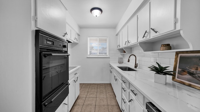 kitchen with white cabinets, decorative backsplash, light stone counters, and sink