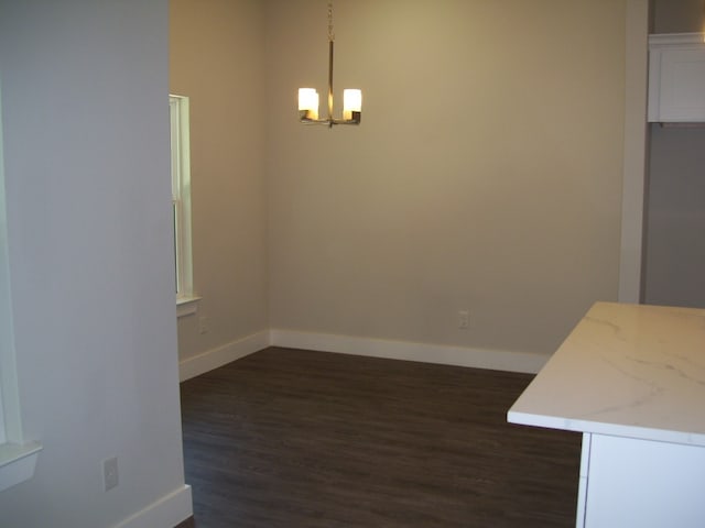 unfurnished dining area featuring a chandelier and dark hardwood / wood-style floors