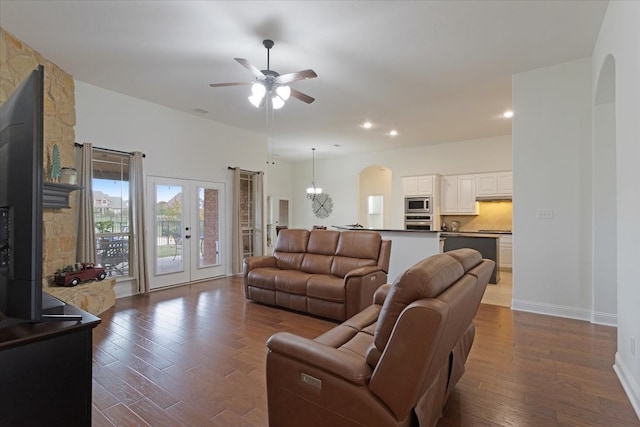 living room with ceiling fan with notable chandelier, dark hardwood / wood-style flooring, and french doors