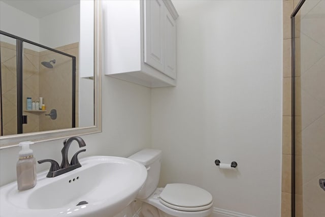 bathroom with sink, a shower with shower door, and toilet