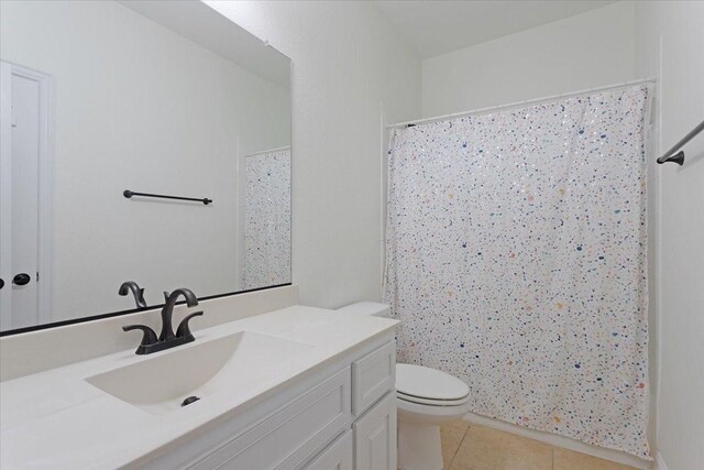 bathroom with tile patterned flooring, vanity, toilet, and curtained shower