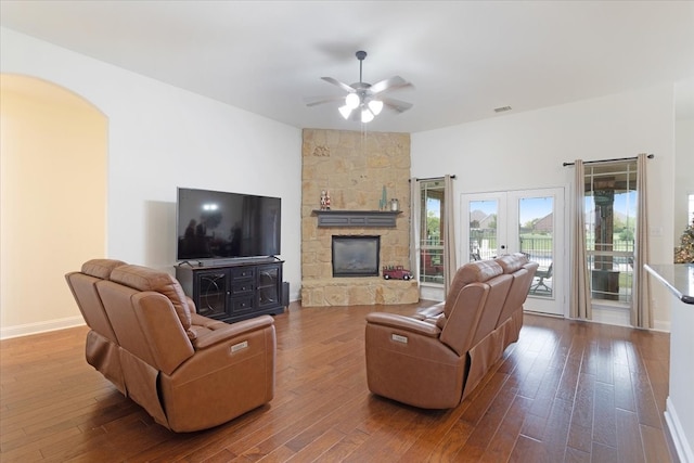 living room featuring french doors, hardwood / wood-style flooring, a stone fireplace, and ceiling fan