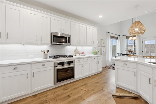 kitchen with appliances with stainless steel finishes, white cabinetry, plenty of natural light, and pendant lighting