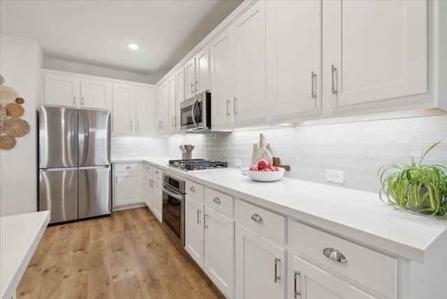 kitchen featuring backsplash, white cabinets, stainless steel appliances, and light wood-type flooring