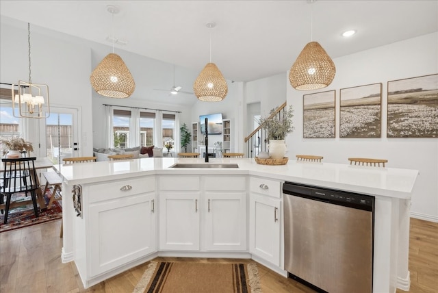 kitchen featuring white cabinets, stainless steel dishwasher, a kitchen island with sink, and hanging light fixtures