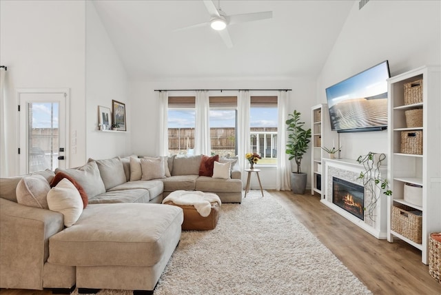 living room with high vaulted ceiling, plenty of natural light, light hardwood / wood-style floors, and ceiling fan