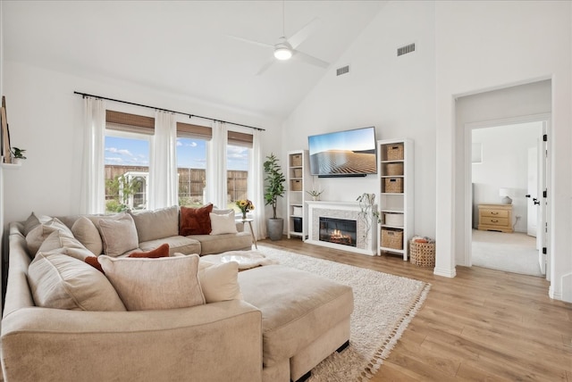 living room with ceiling fan, light hardwood / wood-style flooring, and high vaulted ceiling