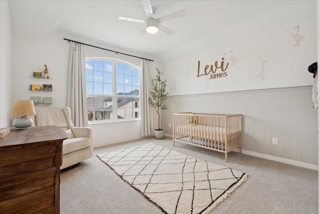 bedroom with light colored carpet, a nursery area, lofted ceiling, and ceiling fan