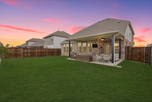 back house at dusk with outdoor lounge area, a yard, ceiling fan, and a patio area