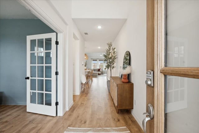 hallway with french doors and light hardwood / wood-style floors