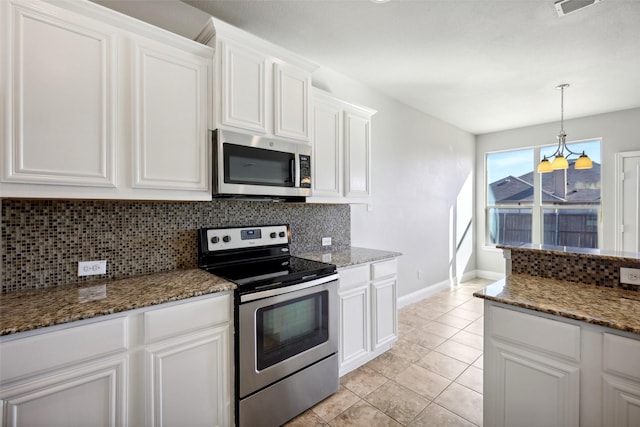 kitchen featuring decorative backsplash, dark stone countertops, light tile patterned flooring, white cabinetry, and stainless steel appliances