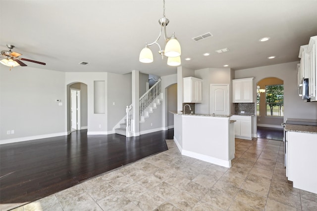 kitchen with ceiling fan with notable chandelier, sink, pendant lighting, white cabinets, and light hardwood / wood-style floors