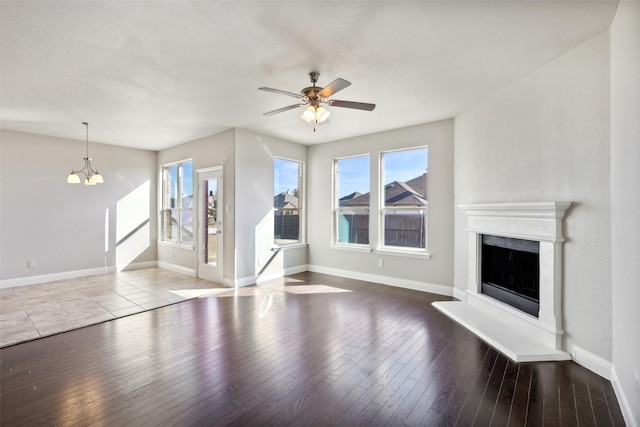 unfurnished living room featuring wood-type flooring, ceiling fan with notable chandelier, and a textured ceiling