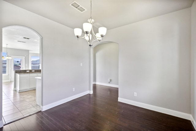 spare room with a chandelier and light wood-type flooring