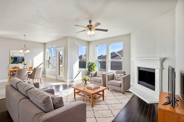 living room featuring ceiling fan with notable chandelier and light hardwood / wood-style flooring