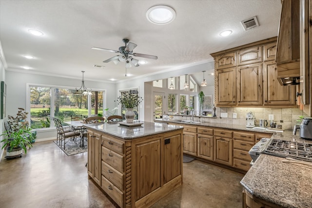 kitchen with pendant lighting, backsplash, crown molding, sink, and a kitchen island