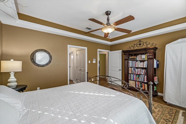 bedroom featuring dark hardwood / wood-style floors, a raised ceiling, ceiling fan, and crown molding