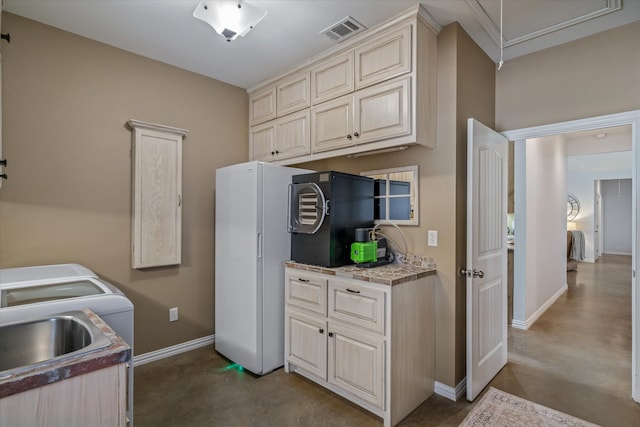 kitchen with cream cabinetry, white fridge, black refrigerator, and sink