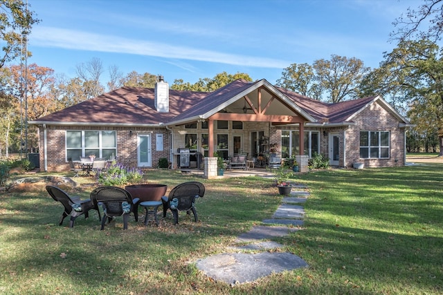 rear view of property featuring a patio, a fire pit, and a lawn