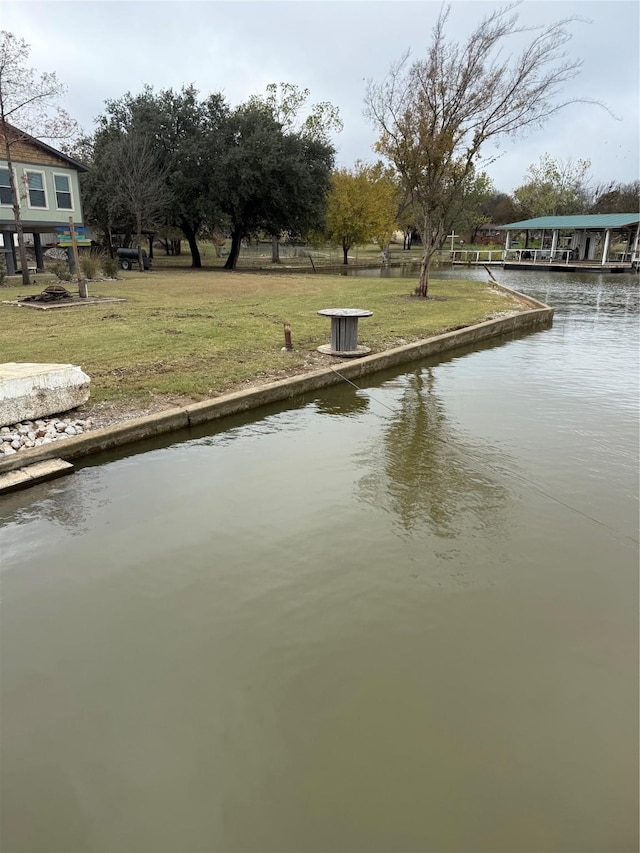 view of dock with a lawn and a water view