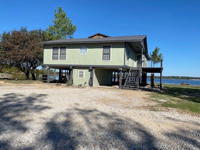 raised beach house featuring a water view and a carport