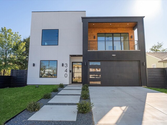 contemporary house featuring a balcony, a garage, and a front lawn