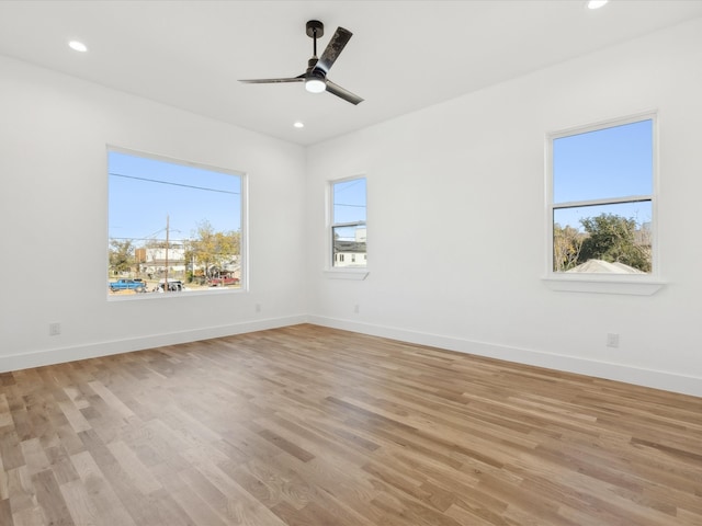 empty room featuring ceiling fan, plenty of natural light, and light wood-type flooring