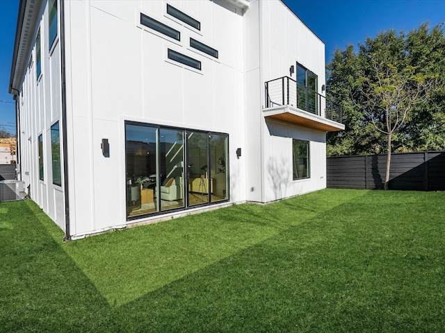 rear view of house featuring a balcony, a yard, and cooling unit