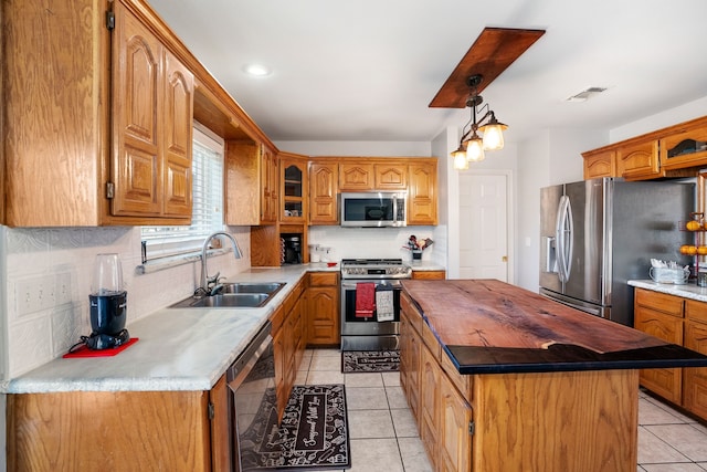 kitchen with stainless steel appliances, a sink, visible vents, light countertops, and glass insert cabinets