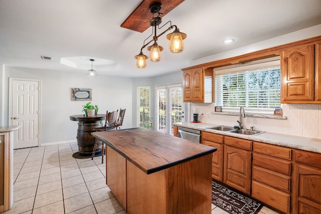 kitchen featuring brown cabinetry, pendant lighting, visible vents, and a sink