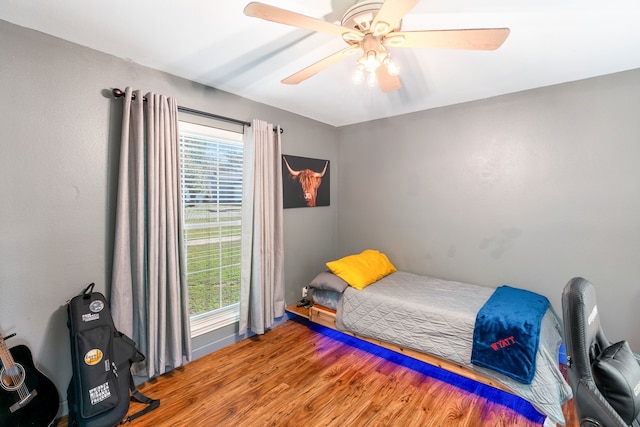 bedroom featuring multiple windows, a ceiling fan, and wood finished floors