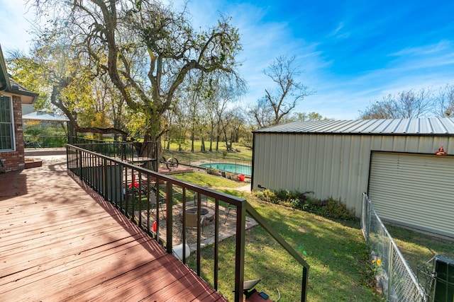 wooden deck featuring fence, an outdoor pool, and a lawn