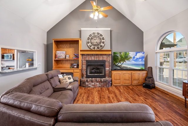 living room featuring ceiling fan, a fireplace, high vaulted ceiling, and hardwood / wood-style flooring