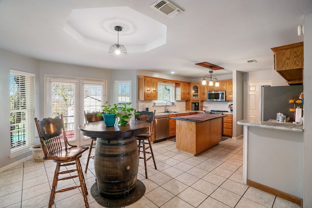 kitchen featuring sink, a center island, stainless steel appliances, decorative light fixtures, and light tile patterned flooring