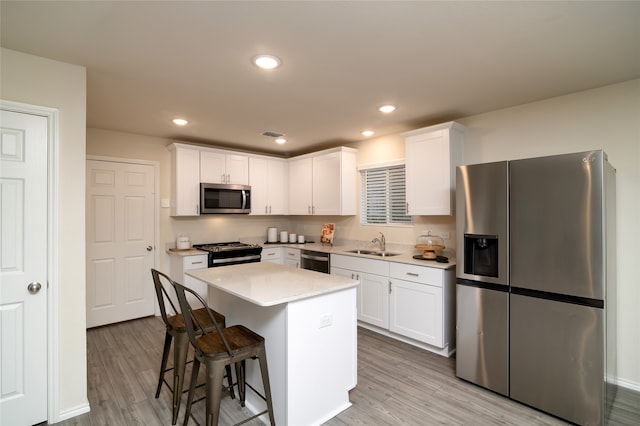 kitchen with light hardwood / wood-style floors, a kitchen island, white cabinetry, and stainless steel appliances