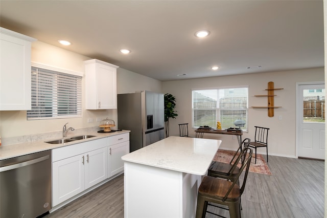 kitchen with a center island, sink, plenty of natural light, white cabinetry, and stainless steel appliances