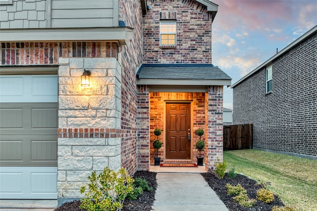 exterior entry at dusk featuring a garage