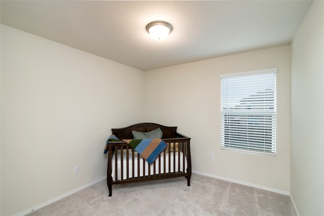 bedroom featuring light colored carpet and a crib