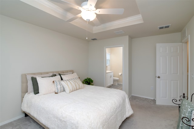 bedroom featuring ensuite bath, light colored carpet, a raised ceiling, and ceiling fan