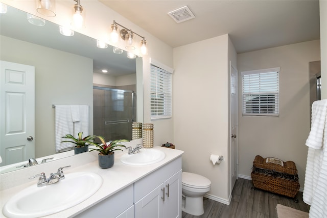 bathroom featuring vanity, wood-type flooring, a shower with shower door, and toilet