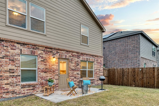 back house at dusk featuring a yard and a patio