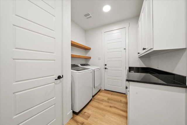 washroom with cabinets, independent washer and dryer, and light hardwood / wood-style flooring