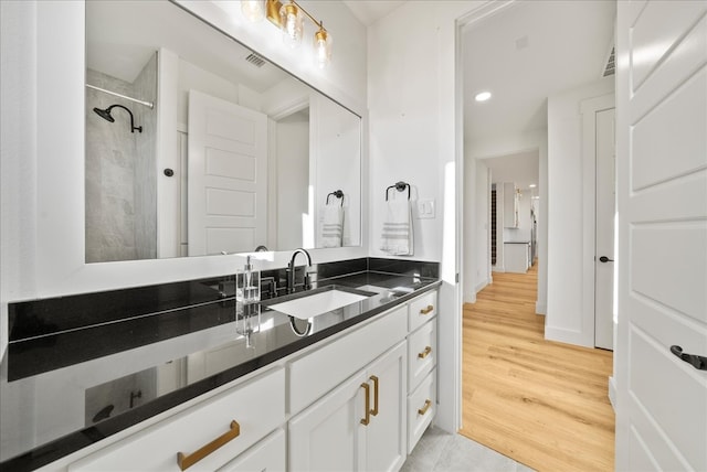 bathroom with vanity, hardwood / wood-style flooring, and tiled shower