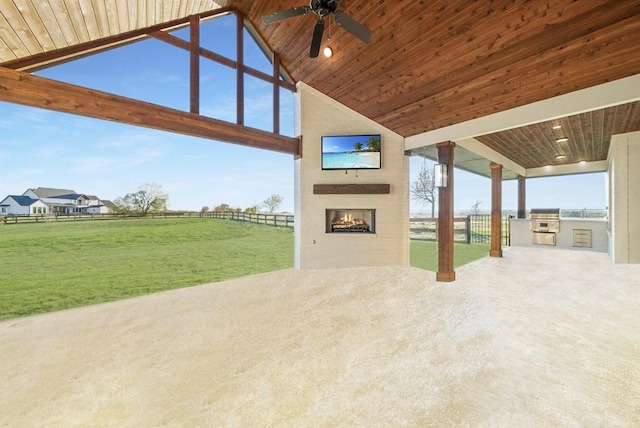 view of patio featuring ceiling fan, area for grilling, a fireplace, and exterior kitchen