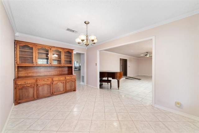 unfurnished dining area with ceiling fan with notable chandelier, light tile patterned floors, a textured ceiling, and crown molding