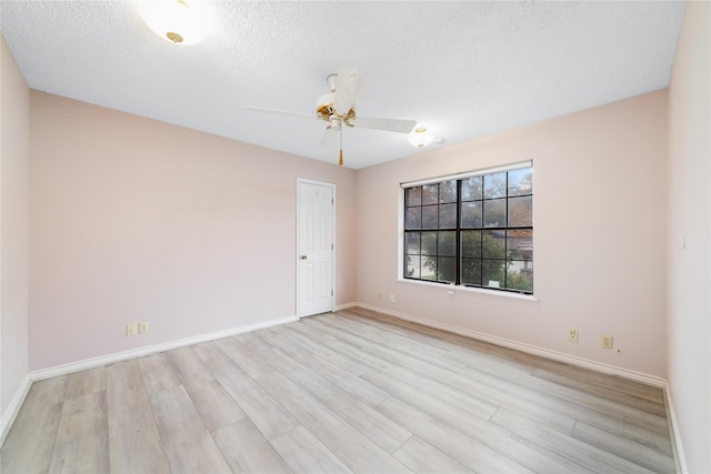 unfurnished room with ceiling fan, a textured ceiling, and light wood-type flooring