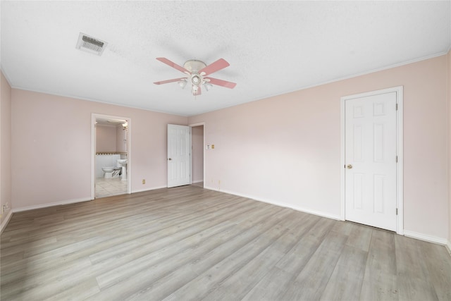 unfurnished bedroom featuring ensuite bathroom, a textured ceiling, ceiling fan, light hardwood / wood-style floors, and a closet