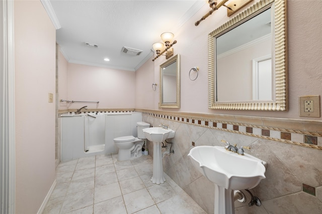 bathroom with tile patterned floors, toilet, ornamental molding, and tile walls